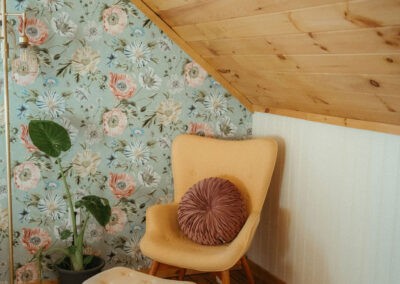 The Loft at The Roost Farm & Market: reading corner with floral wallpaper